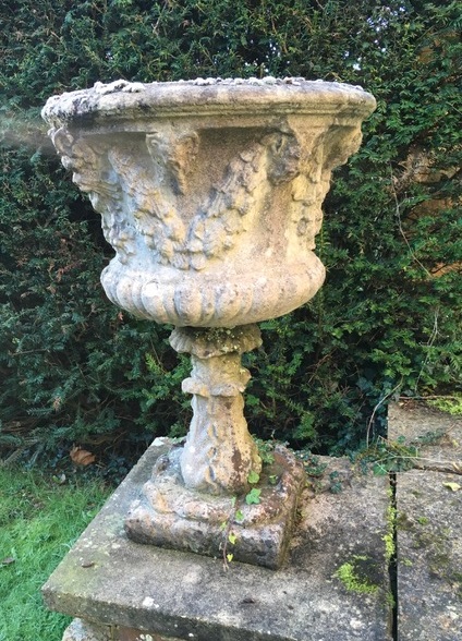 A pair of reconstituted stone garden urns, moulded with floral swags, 84cms